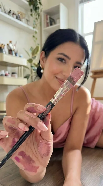 Девушка в розовой шелковой юбке с кистью в первом плане