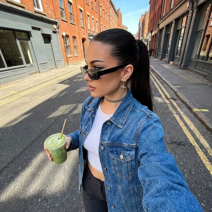 A city fashion girl holding a matcha walks along the red brick streets.