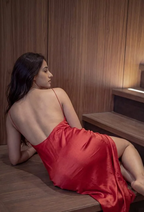Femme fatale en robe rouge, paresseuse sur les escaliers de bois sombre