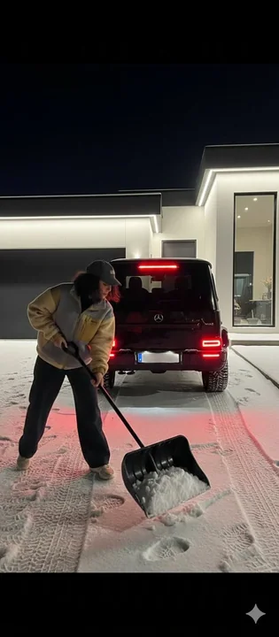 雪の夜、豪邸の前に停まっているベンツと、雪かきをする少女
