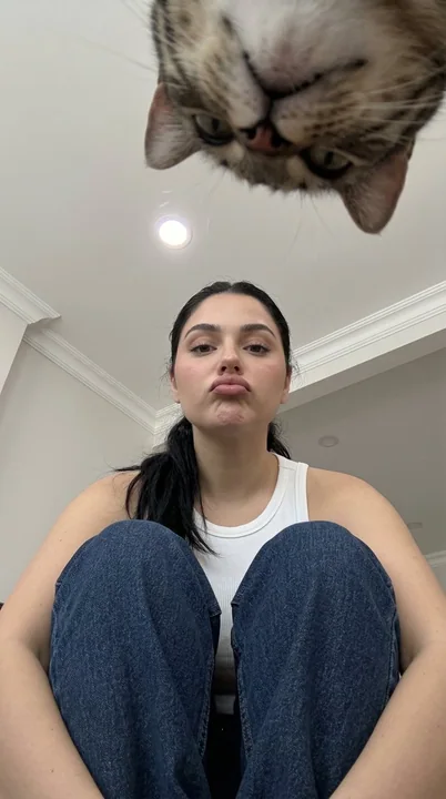 Девушка-кинокамера в ковбойских штанах, сидящая на корточках, с низкой точки зрения