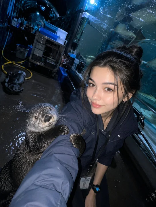 昏暗水族馆隧道里,饲养员与海獭自拍
