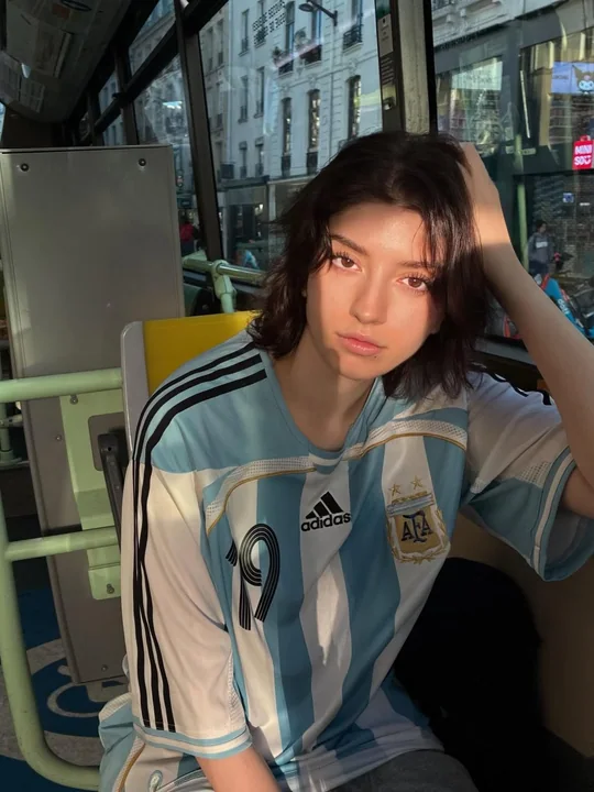 Portrait réaliste de rue en milieu urbain d’un adolescent portant un maillot de l’Argentine