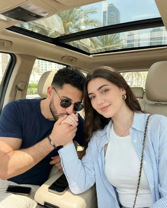 Romantic moment of a couple kissing on the back of hands inside a car with warm sunlight.