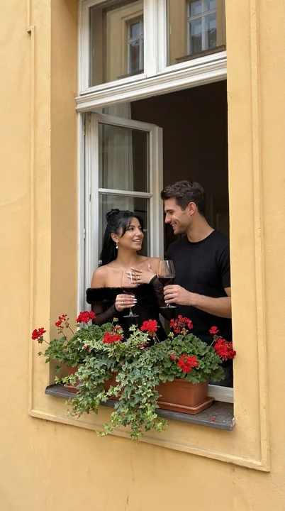 زوجة وعريس يشربان من الكؤوس بالقرب من النافذة مع الجدار الأصفر الأوروبي الرومانسي