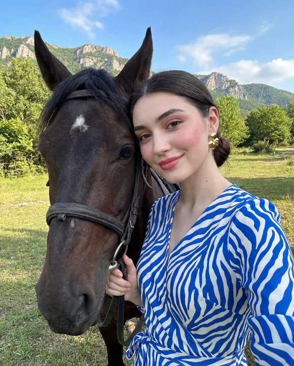 阳光下山脉背景中的时尚人像与马