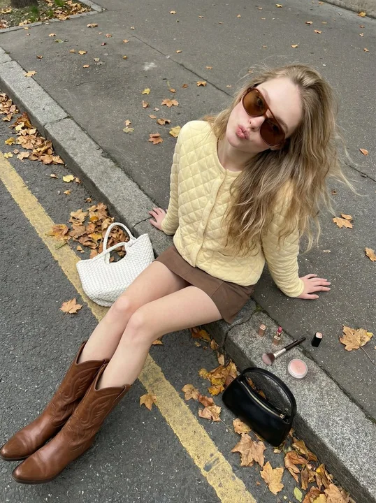 Cute girl on a autumn street, fashionable street style with a yellow cardigan and long boots