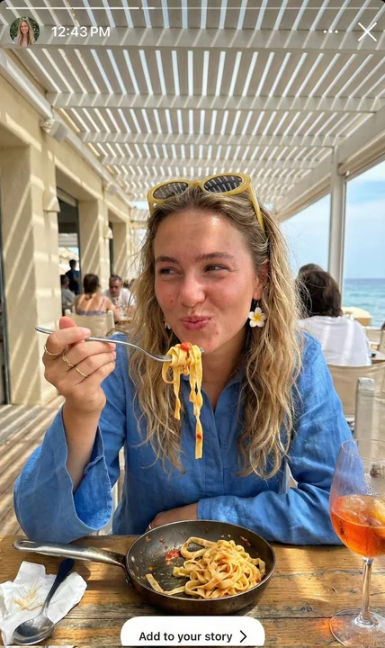 在斑驳阳光下卷起意面的地中海度假少女